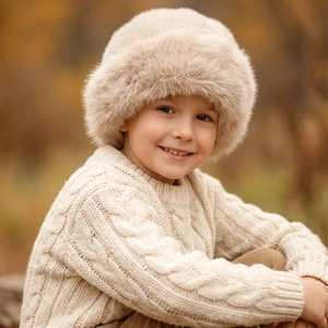 Close-up of fluffy beige faux fur winter hat for kids with thick plush texture