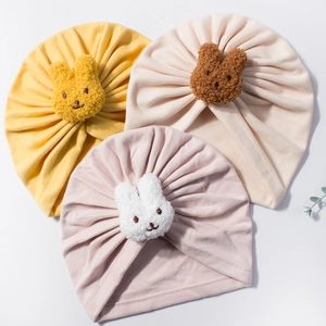 Detailed view of three baby turban hats featuring plush rabbit ears and ribbed fabric