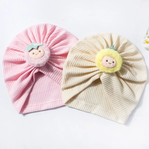Close-up detail of waffle knit baby hats with plush strawberry and pineapple decorations
