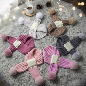 Flat lay of colorful knit scarves with pom-poms on a cozy rug with pine cones
