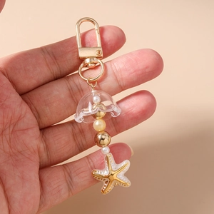 Détail d'un porte-clés marin avec dôme de méduse, perles dorées et pendentif étoile de mer