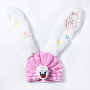 Detailed close-up of pink knit baby hat with white plush bunny ears and embroidery