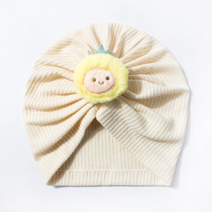 Detailed view of baby waffle knit hat featuring a cute yellow sunflower plush ornament