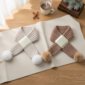 Cozy knit baby cross scarves with pom-poms in cream and beige for winter warmth