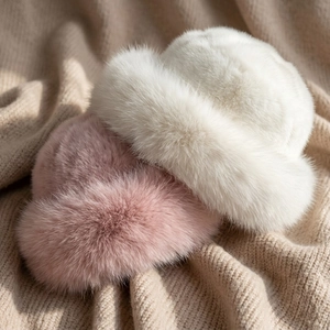 Winter plush Mongolian faux fur hat in white and pink on beige knitted background
