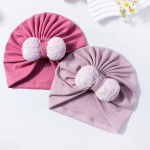 Infant turban hats with large daisy embroidered bows in soft pink and purple tones