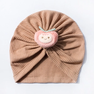 Close-up of waffle knit infant turban hat featuring a 3D plush peach decoration