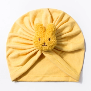 Detail of yellow baby turban hat with a plush rabbit head and soft pleated cotton texture
