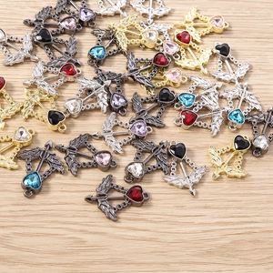 Cupid arrow heart charms with colorful rhinestones on a rustic wooden background