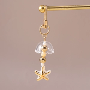 Vue détaillée d'un porte-clés doré thème marin avec étoile de mer et perles