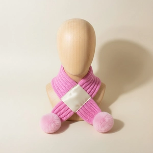 Pink knit baby winter scarf with fuzzy pom-poms and elegant cross-fastening detail
