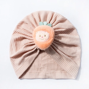 Close-up of pink waffle knit baby hat with a cute orange plush fruit smiling face emoji