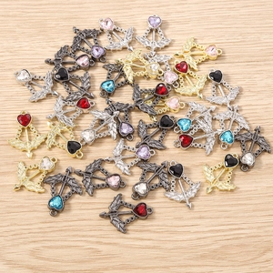 Macro detail of Cupid arrow heart charms in assorted metallic finishes and rhinestone colors