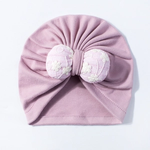 Detail of baby turban hat in lotus pink with embroidered floral bow and pleated knit fabric