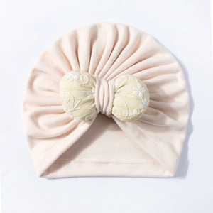Detailed view of pink baby hat with large embroidered yellow floral bow decoration
