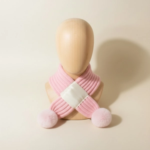 Detailed view of pink knitted baby scarf with soft faux fur pompom and satin cross loop