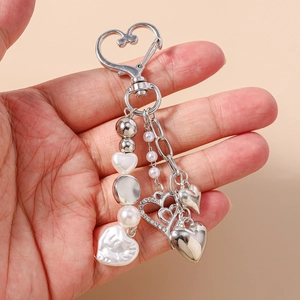 Détail du porte-clés coeur avec perles blanches, strass et breloques en argent poli