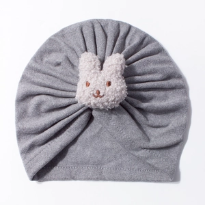 Close-up of grey knit baby turban hat featuring a 3D plush bunny patch detail