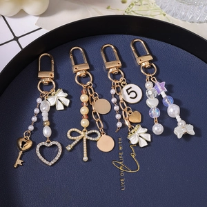 Goldenes Schlüsselanhänger-Set mit weißen Perlen, Herzanhängern und Schleifen
