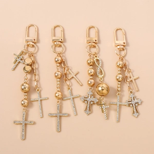 Chic gold-tone beaded keychain featuring rhinestone cross and infinity charms in a luxury style