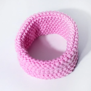 Close-up of pink knitted baby neck warmer showing thick honeycomb texture and soft yarn