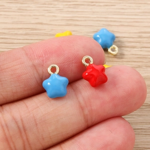 Gros plan de pendentifs étoiles en émail coloré rouge, jaune et bleu pour bijoux DIY