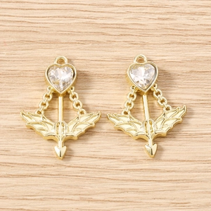 Macro detail of gold Cupid arrow heart charms with wings and clear zircon stone