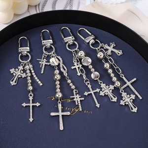 Detail view of four silver cross keychains with beads and rhinestones in a blue tray