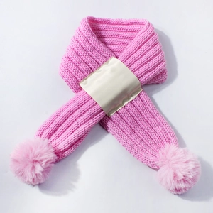 Close-up of pink knit baby scarf with soft faux fur pom-poms and cream satin cross strap
