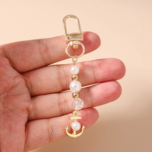 Vue détaillée d'un charm ancre dorée avec perles et billes sur un porte-clés élégant