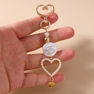 Detail of heart-shaped spring clasp and baroque pearl charm on golden keychain