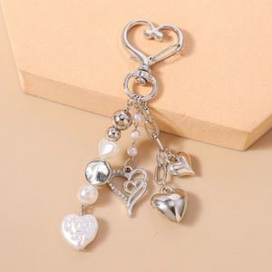 Détail du porte-clés cœur avec perles et strass posé sur un support beige doux