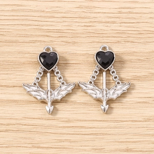 Detailed macro of two gothic silver heart pendants with black gems on wood background