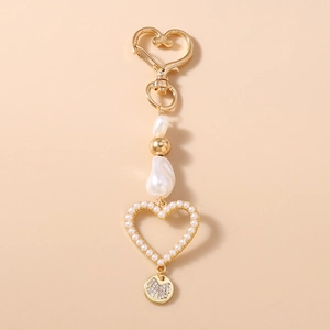 Detail of baroque pearl heart keychain with golden heart clasp and bow charm detail