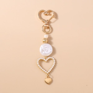 Detail of a golden heart keychain with irregular pearls and hollow heart frame pendant