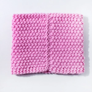 Macro detail of pink chunky knit baby neck warmer showing soft textured grain and fabric