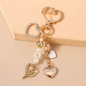 Gros plan du porte-clés cœur doré avec gravure Love You, perles et breloques strass