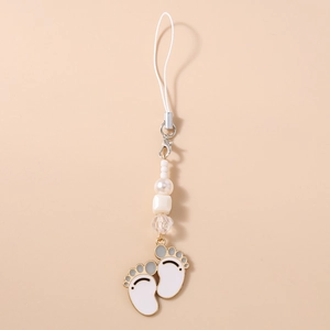 Close-up of white enamel footprints charm with pearls and crystal beads on a phone strap