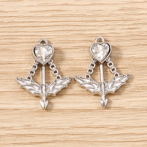 Macro detail of silver Cupid arrow pendants with heart-shaped crystal on wood surface