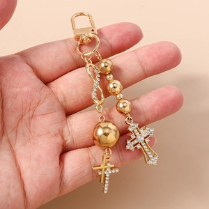 Detail view of gold beaded keychain with rhinestone cross and infinity charm on hand