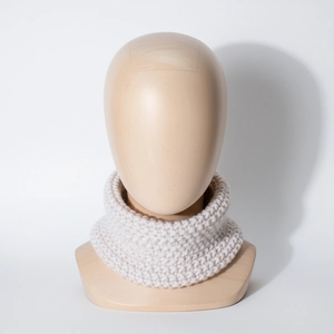 Detailed knit texture of cream-colored winter neck warmer for babies on wooden model