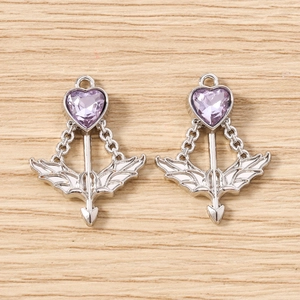 Macro detail of Cupid arrow heart pendants with purple faceted gemstones and silver finish