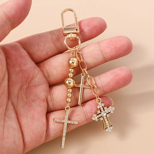 Detailed close-up of three gold cross charms with rhinestones on a beaded keychain