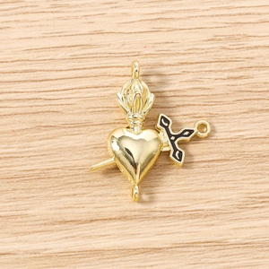 Détail macro du connecteur cœur et dague doré avec émail noir pour création de bijoux DIY