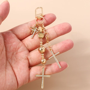 Detail of hand-held gold beaded keychain with rhinestone cross pendants and spring ring
