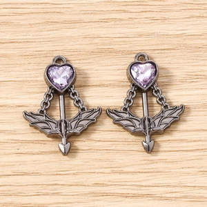 Detailed view of dark metal Cupid's arrow pendants with purple heart-shaped gemstones