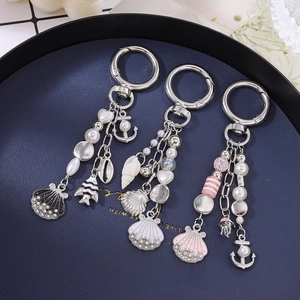 Ocean theme keychain with pearls, anchor, seashell and fish charms on blue tray