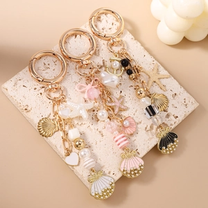 Chic ocean themed keychain with gold seashell starfish and pearl charms on stone