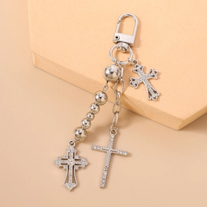 Detail of silver beaded keychain with rhinestone cross pendants on a minimal background