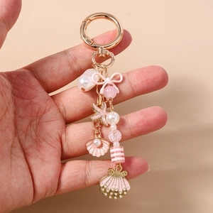 Detail view of pink starfish, shell, and pearl charms on a golden metal keychain